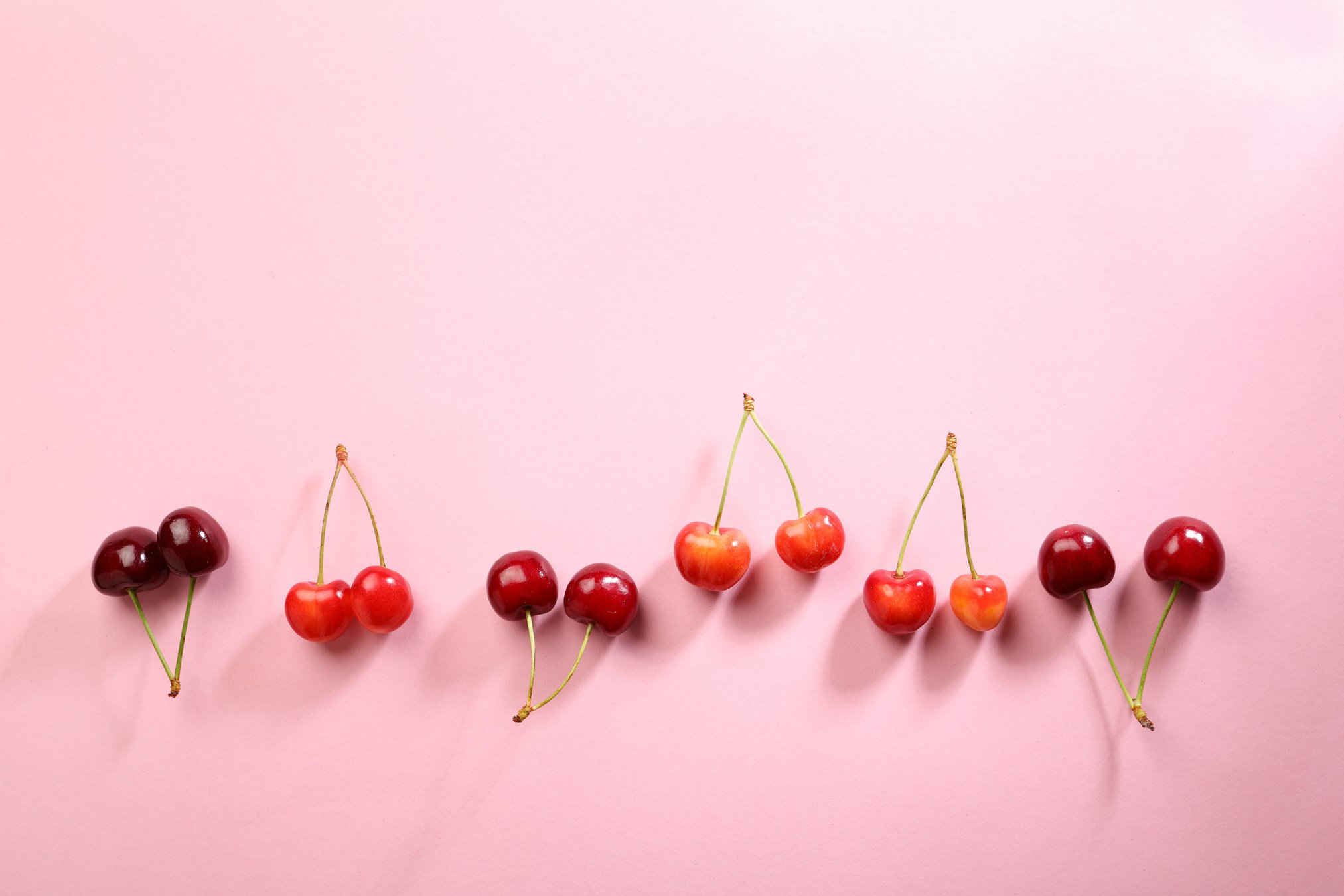 Fresh cherries on pink background, food above